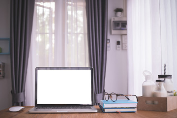 wood table with blank screen on laptop, notebook paper and a lot of milk on box carton in living room.