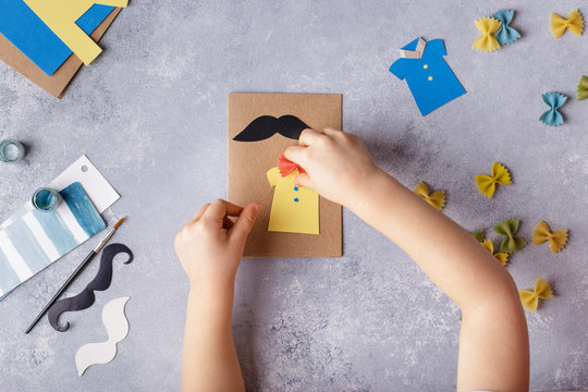 Making greeting card for Fathers Day. Shirt with butterfly from pasta. Card from paper. moustache. Childrens art project. Step-by-step photo instruction. Child makes card layout. Top view