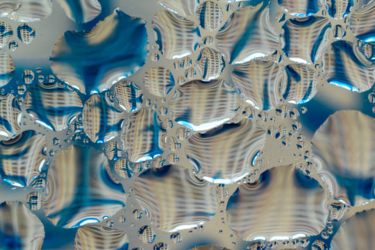 Macro photo. Abstract aqua pattern as background. Twisted reflections in water droplets. Blue lines and multi-storey building.