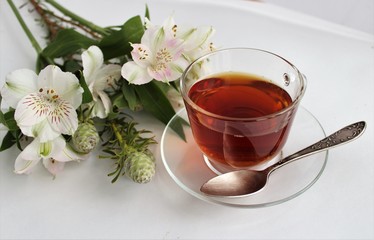 Black fragrant tea and brown cane sugar in a glass sugar bowl on a white background.