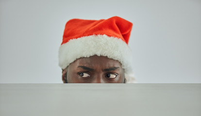 The african man in the santa hat watching from the table
