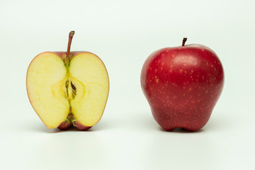 one whole red apple and half an apple next to it on a white background