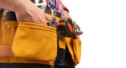 Lateral view of constructor holding hands inside tool belt pockets.