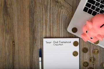 Year-End financial checklist. Pink piggy bank close to the laptop.