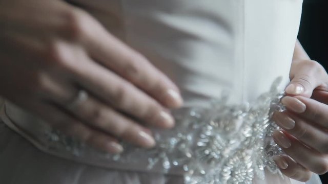 Close up hands of bride touching goffering belt.