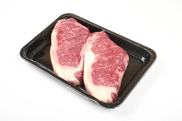 Raw steak in an airtight vacuum package on a white background.