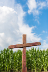 Christian wooden cross on the background of the sky in clouds and agricultural field