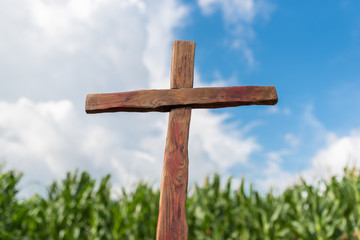 Christian wooden cross on the background of the sky in clouds and agricultural field