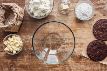 top view of empty glass bowl and ingredients for delicious homemade cake on wooden table