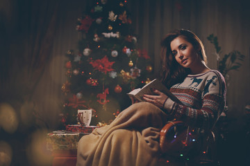 Woman reading a book near Christmas tree