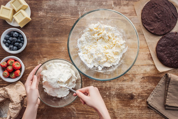 partial top view of woman preparing dough and cream for delicious cake