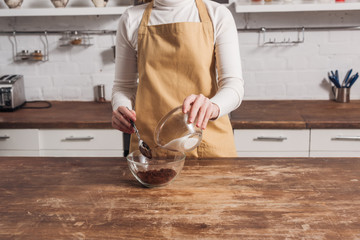 mid section of woman in apron mixing ingredients and preparing delicious sweet cake