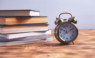 books and an alarm clock on a wooden background