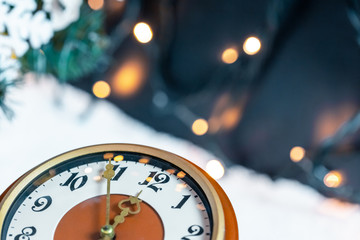 Fototapeta na wymiar Vintage alarm clock on snow on blur background of Christmas tree. New Year Theme
