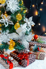Christmas gifts in the snow under the tree. The concept of home holiday, surprises and present