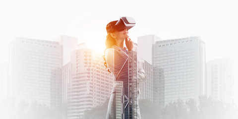 Woman in mask against sunrise above city trying virtual reality