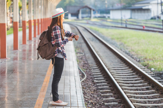 Beautiful young asian woman traveler looking clock  with brown bag ,Waiting for train at train station, Chinese tourists, Travel and vacation concept.
