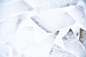 Winter pavement background. Snow covered wild stone paving tiles.