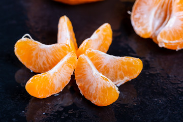 Beautiful ripe tangerines with leaves and water drops on a dark background.