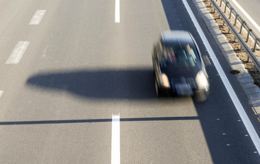 Aerial view of a car driving fast on the highway with three lanes and road fence barrier