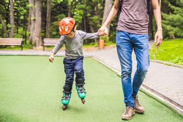Dad teaches son to rollerblade in the park