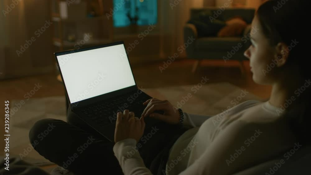 Wall mural evening at home: young woman resting on a couch using with white mock-up screen laptop computer. gir