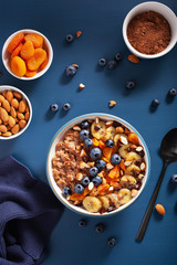 chocolate oatmeal porridge with blueberry, nuts, banana, dried apricot for healthy breakfast. Top view