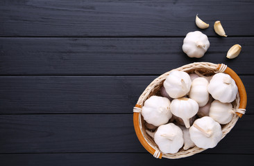 Fresh garlic in basket on a black wooden background
