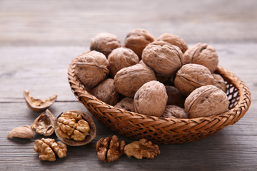 Walnuts kernels in basket on grey wooden background