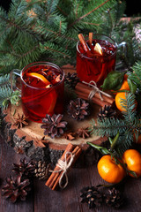 Fototapeta na wymiar Hot winter tea with cinnamon on wooden background. Fir branches and tangerines nearby. The concept of new year or Christmas holidays. Still life with tea and fir branches.