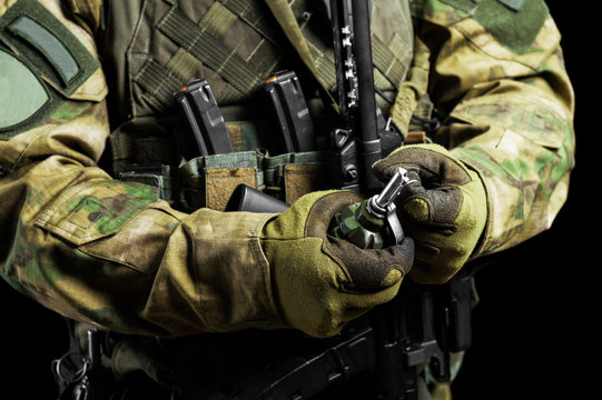 Soldier in full combat ammunition pulls a check from a grenade.