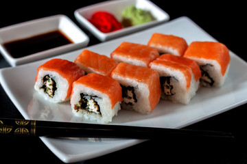 Traditional Japanese cuisine. Philadelphia sushi roll made of fresh salmon, avocado and cream cheese with black rice
