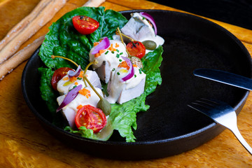 delicious Restaurant Dish Vitello Tonato in restaurant background. Healthy exclusive food on big black platter closeup