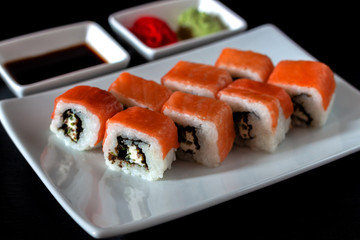Traditional Japanese cuisine. Philadelphia sushi roll made of fresh salmon, avocado and cream cheese with black rice