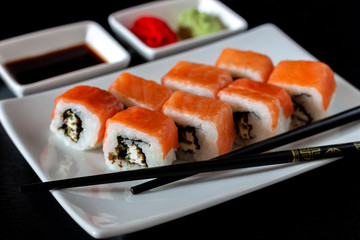 Traditional Japanese cuisine. Philadelphia sushi roll made of fresh salmon, avocado and cream cheese with black rice