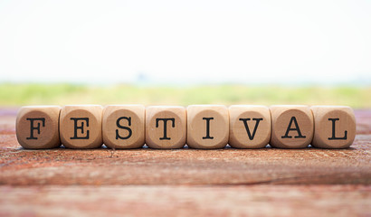 FESTIVAL word written on cube shape wooden blocks on wooden table.