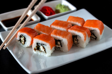 Traditional Japanese cuisine. Philadelphia sushi roll made of fresh salmon, avocado and cream cheese with black rice