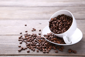 Coffee beans in cup on grey wooden background.