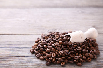 Coffee beans in wood spoon on grey background.