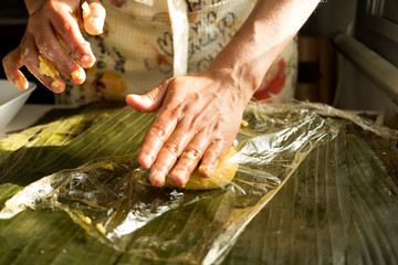 close up of hands of young woman making venezuelan christmas dish hallacas with platan leaf