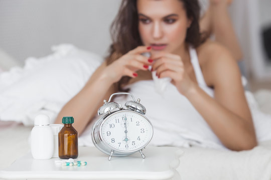 Sick woman lying in the bed. Girl taking medicine from the flu. Female got cold.