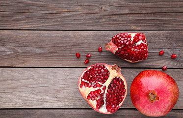Pomegranate and half of ripe pomegranate on a grey wooden background
