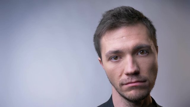 Closeup of face of attractive caucasian man looking straight at camera listening and nodding with a serious facial expression