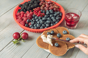 Waffles with cheese, yogurt and raspberries. A delicious wholesome breakfast on a light background. Very soft selective focus.
