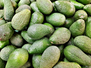 Green fresh avocados lie in the shop window