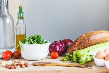 ingredients for salad, fresh vegetables, olive oil, nuts on the table in the kitchen. culinary and food concept