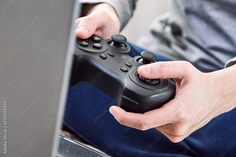 Poster man holding a joystick controllers while playing a video games at home