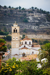 Fototapeta na wymiar A large white the holy cross church with a red tile roof and a tower with a bell tower in the Lefkara village mountains Troodos on the island of Cyprus