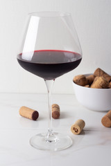 a glass of red wine and wine corks on a white background.