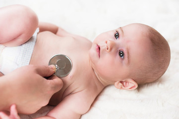 A small child lies at the doctor's office close-up. Listen to the lungs and heart. Abstraction health